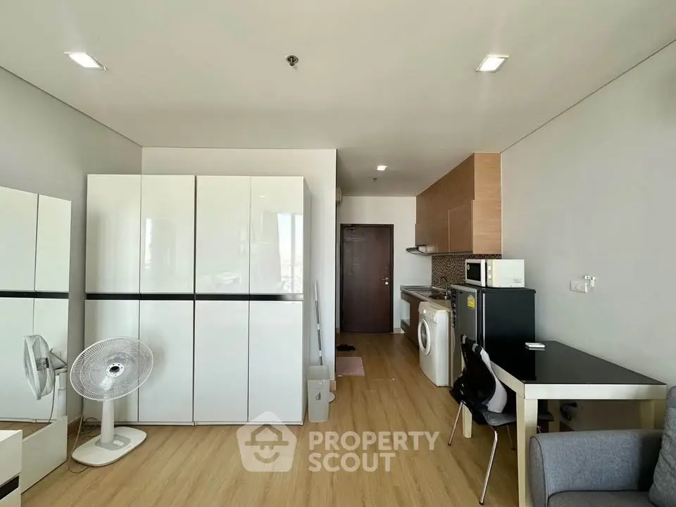 Modern studio apartment with sleek kitchen and washing machine, featuring minimalist design and ample storage.