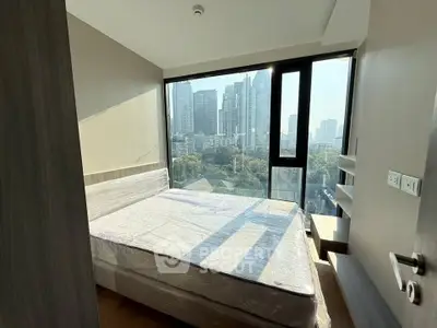 Modern bedroom with large windows offering stunning city views in a high-rise apartment.