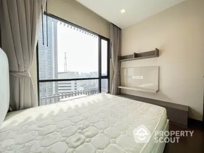 Modern bedroom with large windows offering stunning city views in a high-rise apartment.