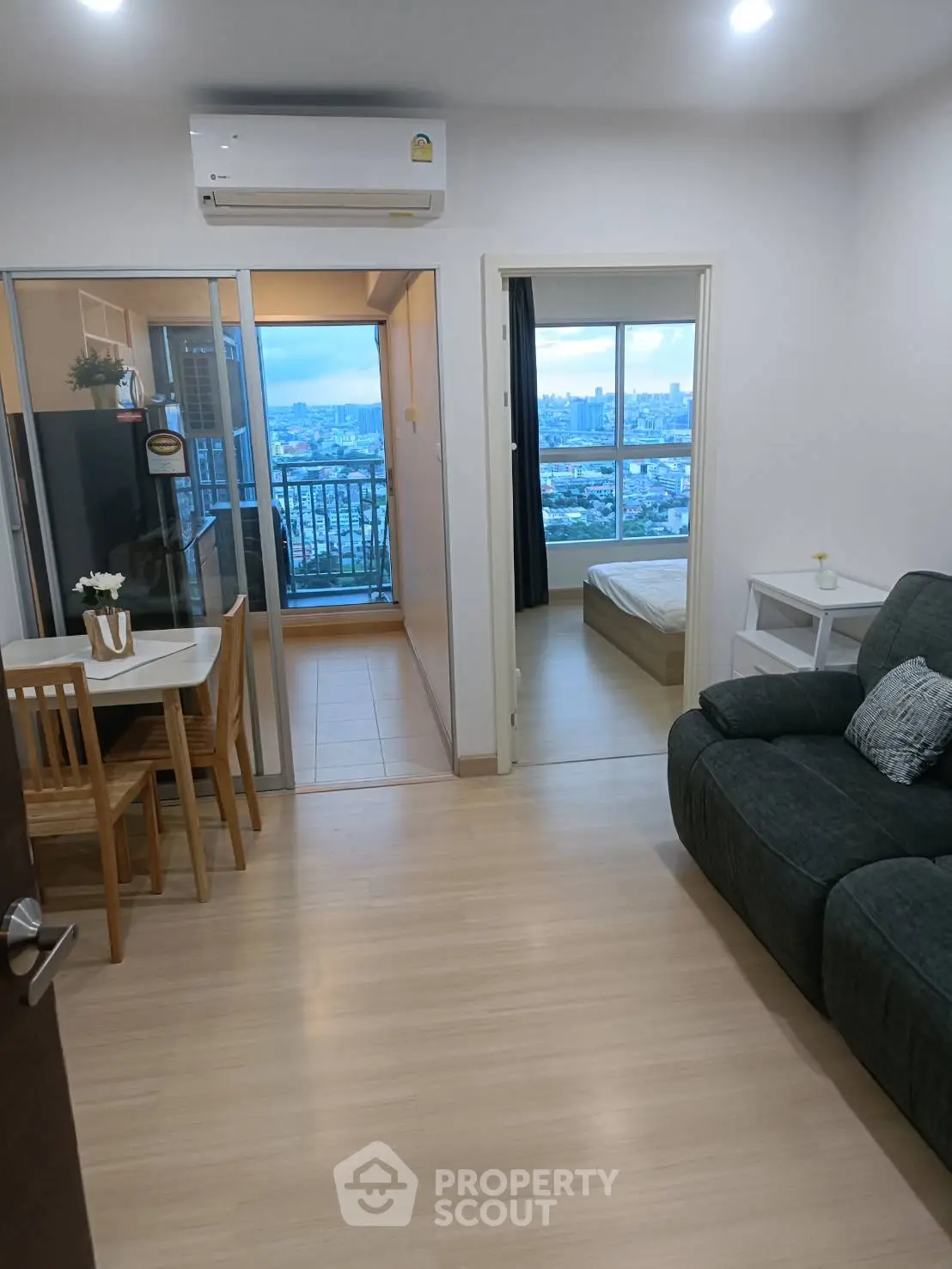 Modern apartment interior with open living area and city view from balcony.