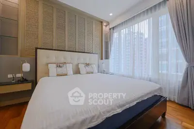 Luxurious bedroom with elegant decor and large windows offering city views.