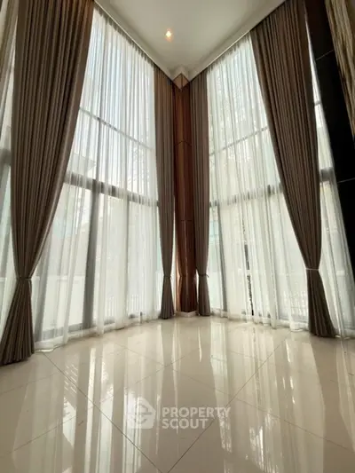 Spacious corner unit with floor-to-ceiling windows and elegant curtains