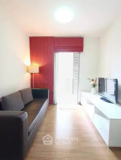 Cozy living room with modern sofa and TV unit, featuring bright natural light and stylish red curtains.