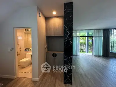 Spacious modern living area with open layout and garden view, featuring sleek wooden flooring and elegant design.
