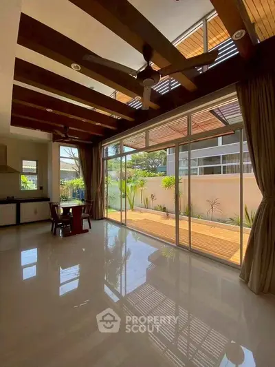 Spacious living room with high ceilings and large windows opening to a private patio.