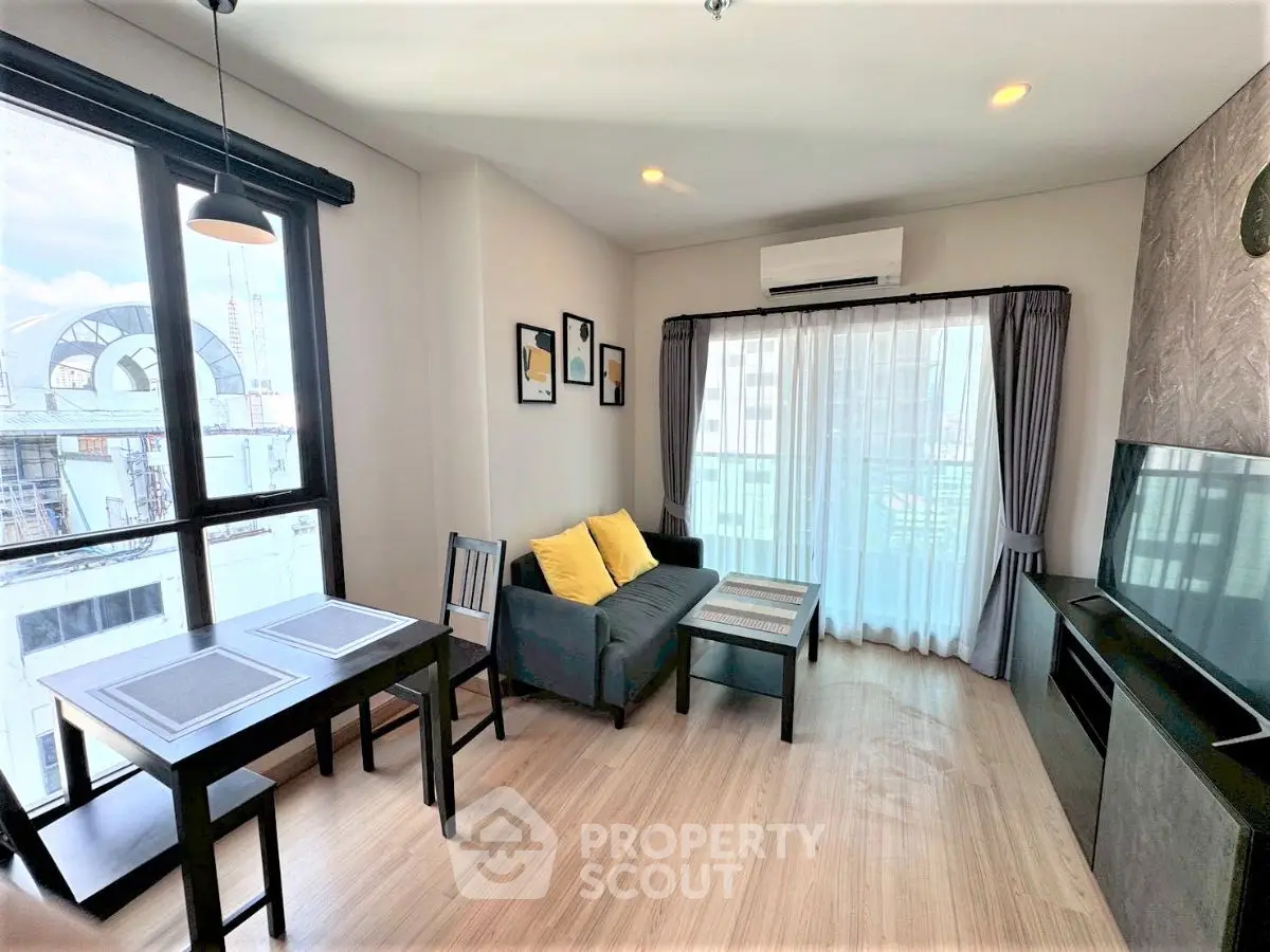 Modern living room with large windows and stylish decor in urban apartment.