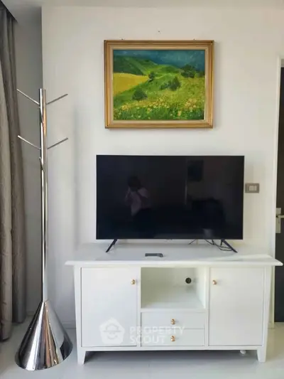 Modern living room with sleek TV stand, stylish coat rack, and vibrant landscape painting.