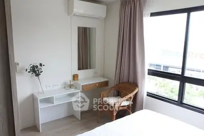 Cozy bedroom with wicker chair and large window offering natural light.