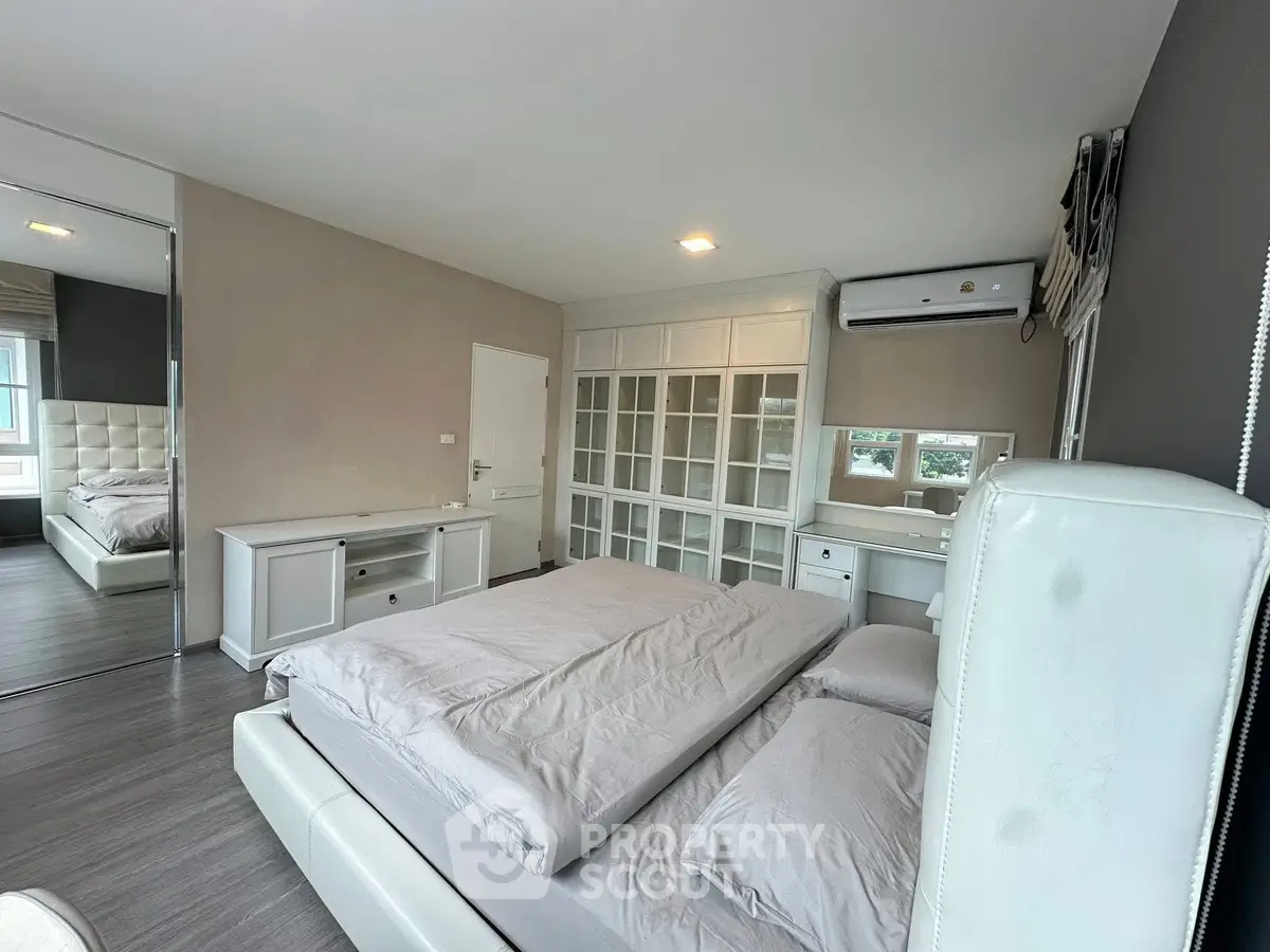 Spacious bedroom with modern decor and large windows offering natural light