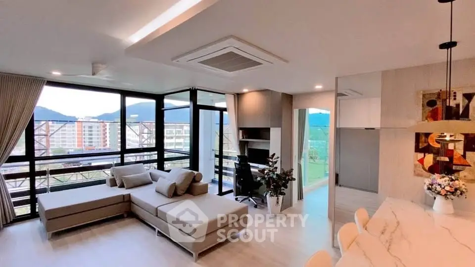 Modern living room with large windows and mountain view, featuring stylish furniture and open layout.
