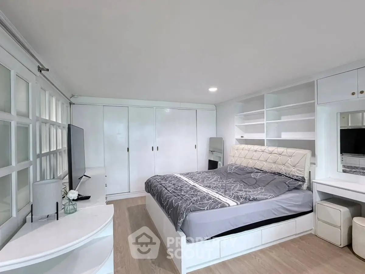 Spacious bedroom with modern white furnishings and built-in storage solutions