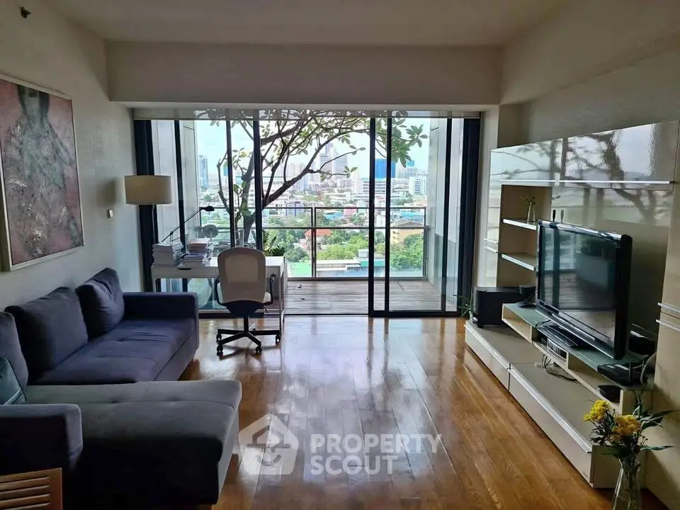 Spacious living room with city view and balcony access, featuring modern furniture and natural light.
