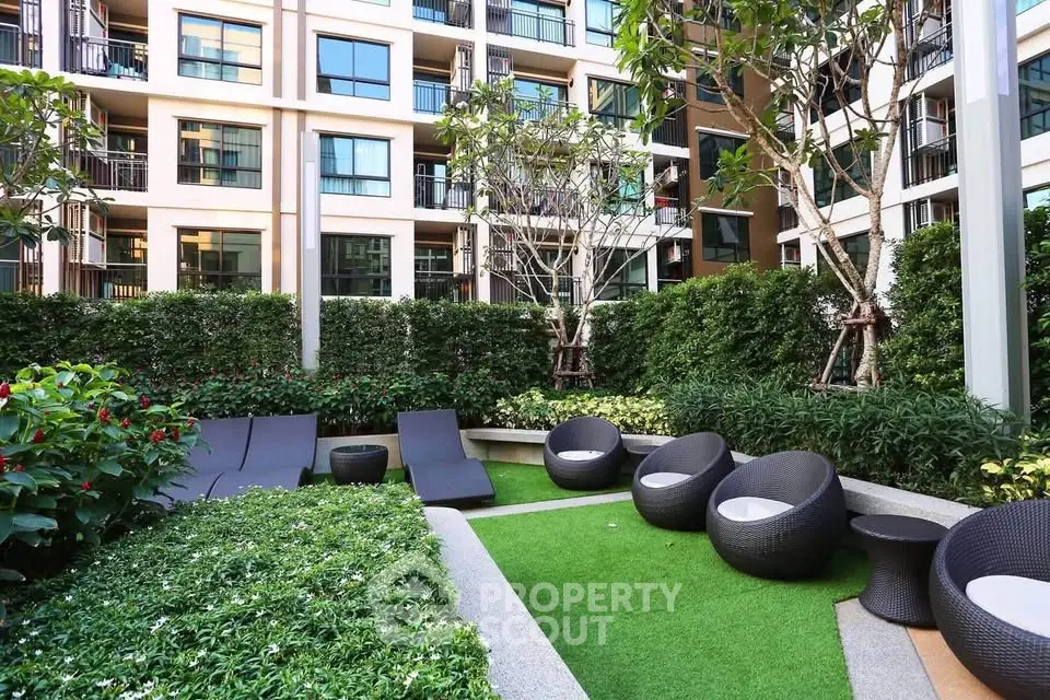 Modern apartment building with lush garden and stylish outdoor seating area.