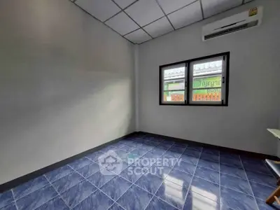 Spacious empty room with blue tiled floor and air conditioning, perfect for customization.