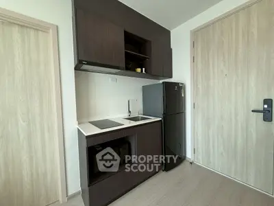 Modern compact kitchen with sleek cabinetry and appliances in a stylish apartment.