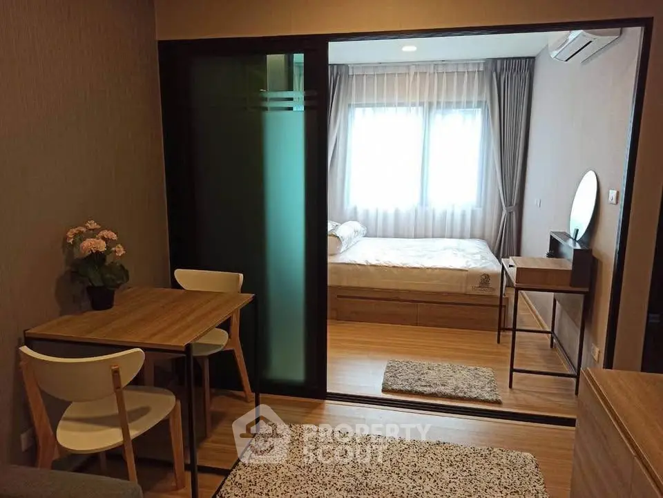 Cozy modern apartment with wooden flooring and sliding glass door separating bedroom and living area.