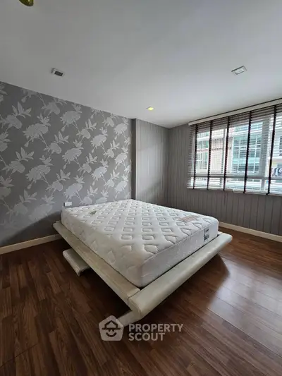Spacious bedroom with modern decor and large window offering natural light.