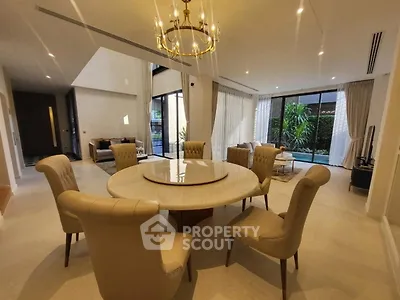 Luxurious open-plan living room with elegant dining area and pool view, featuring modern decor and natural light.