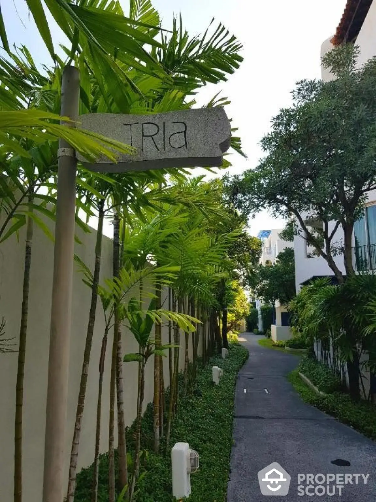 Charming garden pathway at Tria residential complex with lush greenery and modern architecture.