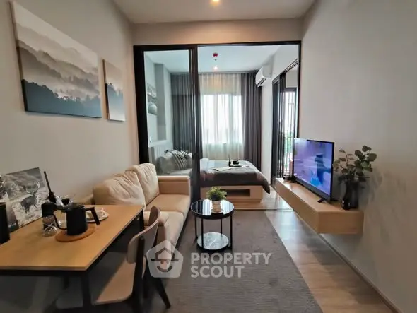 Modern living room with cozy seating and TV, adjacent to a stylish bedroom.