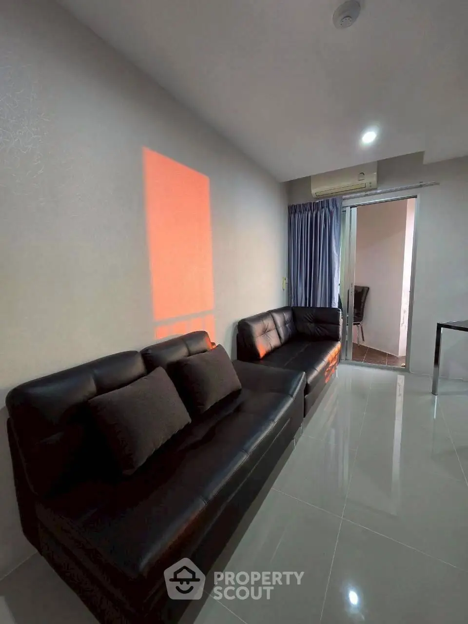 Modern living room with sleek black sofas and glossy tiled floor, featuring ambient lighting and stylish decor.