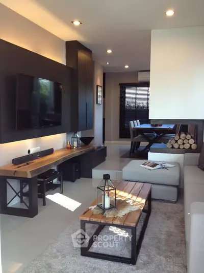Modern living room with sleek furniture and stylish decor, featuring a wall-mounted TV and cozy seating area.