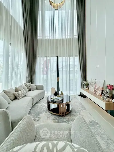 Luxurious high-ceiling living room with elegant decor and large windows