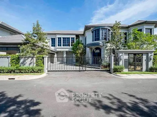 Luxurious modern mansion with gated entrance and lush landscaping