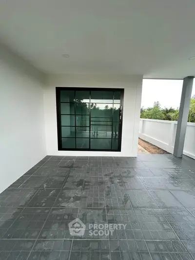 Spacious balcony with modern sliding glass doors and tiled flooring, perfect for outdoor relaxation.