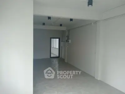Spacious empty room with modern lighting and large window, ideal for customization.