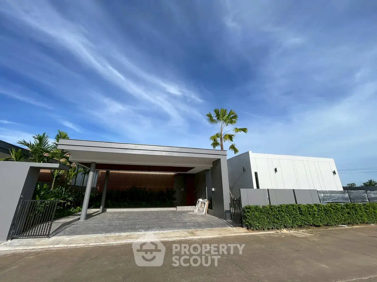 Modern single-story home with sleek design and spacious driveway under a clear blue sky.