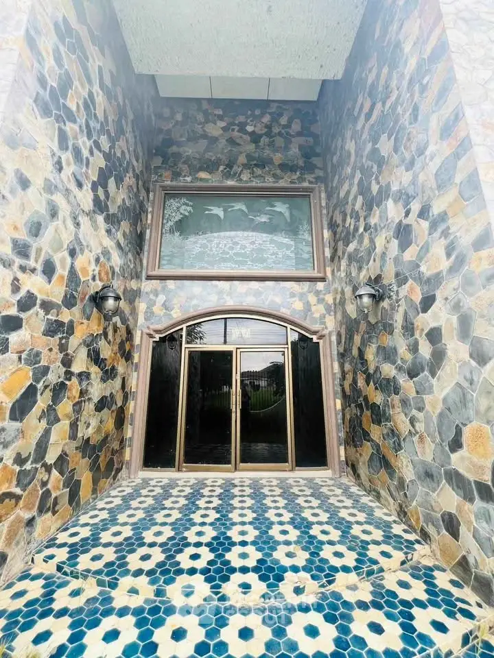 Stunning stone facade entrance with intricate tile flooring and elegant glass doors.