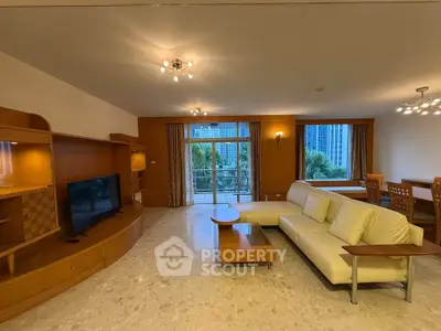 Spacious living room with modern furniture and large windows offering a lush garden view.