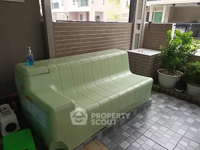 Spacious balcony with green storage bench and potted plants, perfect for relaxation.