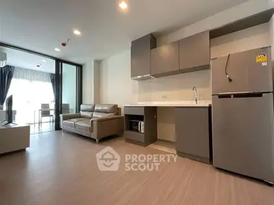 Modern open-layout living room with kitchen and balcony access, featuring sleek furniture and natural light.