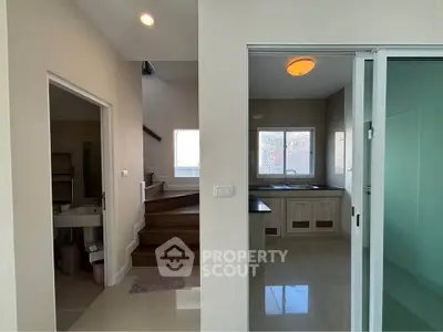 Modern interior with kitchen and staircase, featuring sleek design and natural light.