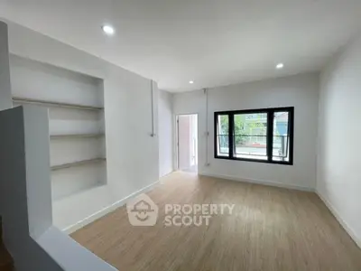 Spacious modern living room with large window and built-in shelves, perfect for natural light lovers.