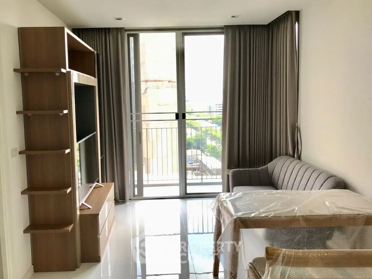 Modern living room with balcony, featuring sleek furniture and natural light.