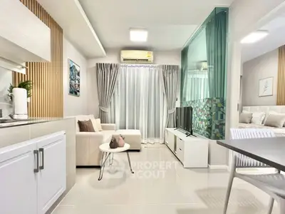 Modern open-plan living room with sleek kitchen and cozy seating area, featuring elegant decor and natural light.