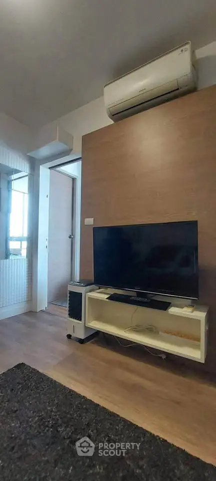 Modern living room with TV and air conditioning, featuring sleek wooden accents and cozy atmosphere.