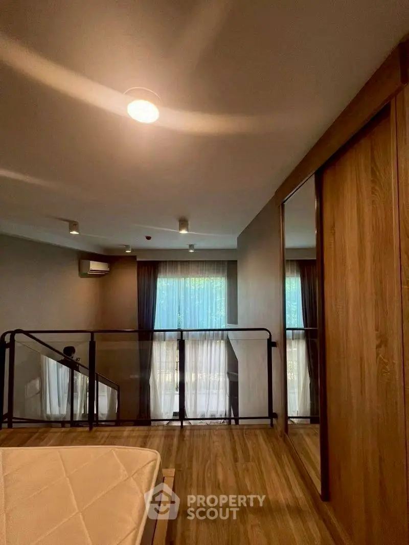 Modern bedroom with wooden flooring and large windows, featuring a sleek design and ample natural light.
