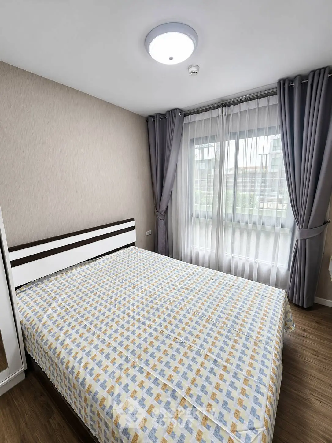 Cozy bedroom with large window and modern decor in a stylish apartment.