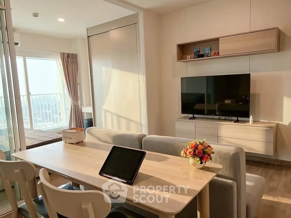Modern living room with dining area and balcony view, featuring sleek furniture and natural light.