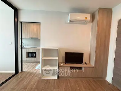 Modern living room with sleek design and built-in storage, featuring a compact kitchen area.