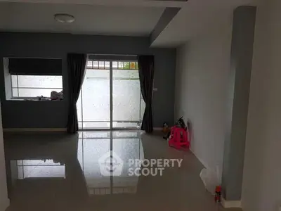Spacious living room with large window and modern tile flooring