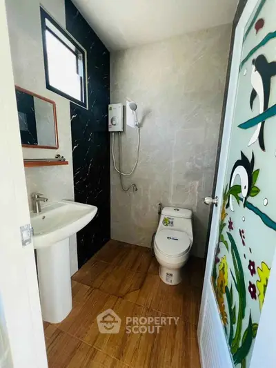 Modern bathroom with stylish decor and wooden flooring, featuring a shower and elegant sink.