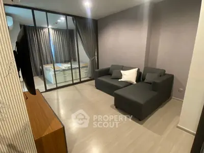 Modern living room with sleek furniture and glass partition to bedroom