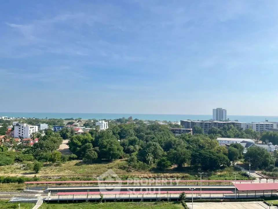 Stunning coastal view from high-rise building overlooking lush greenery and ocean horizon.