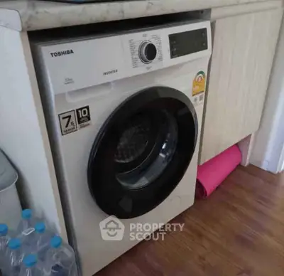 Modern washing machine in a stylish laundry area with wooden flooring.