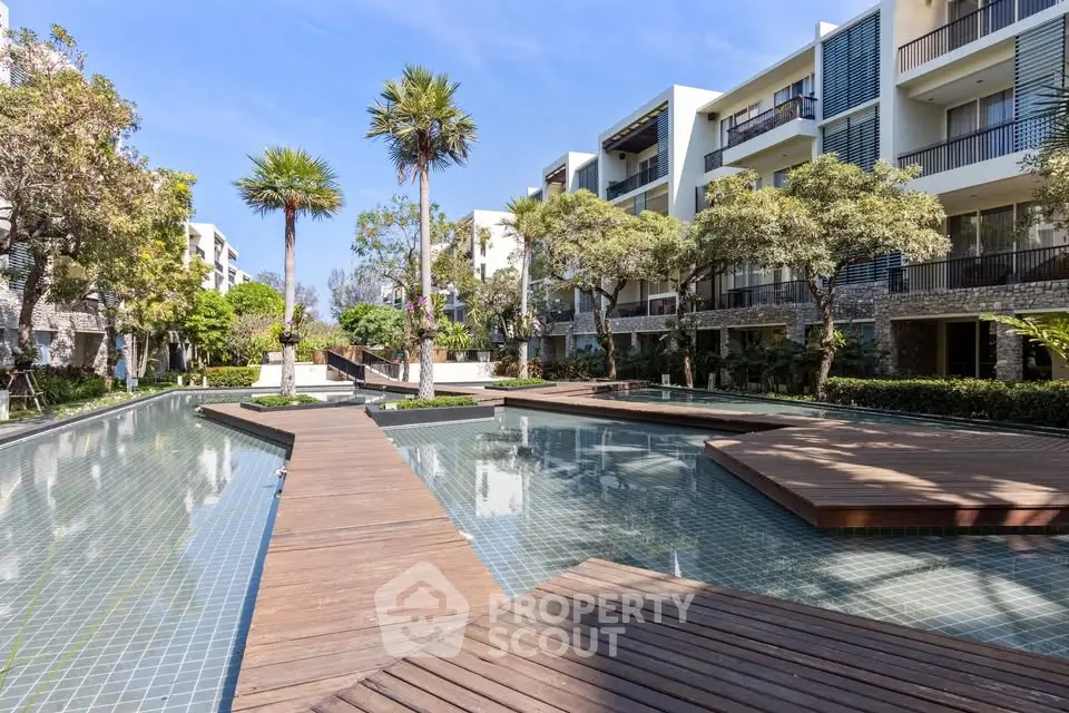 Luxurious modern apartment complex with serene pool and lush greenery, perfect for tranquil living.